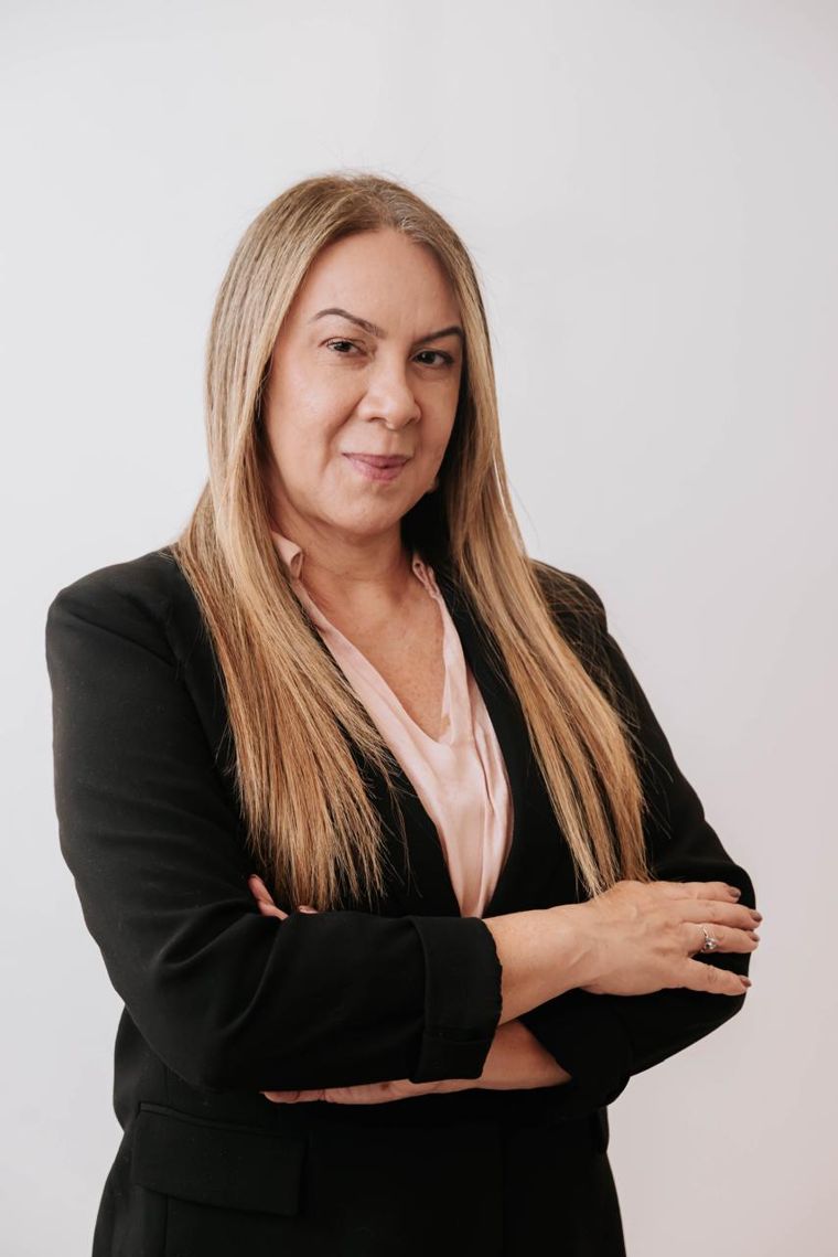 Retrato da advogada Sylvia Drummond, de blazer preto e braços cruzados
